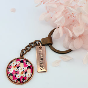 Circle pendant keychain in vintage copper with 'fearless' charm, bright pink floral print. Fundraiser for the national breast cancer foundation.