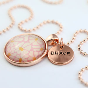 Circle pendant necklace in rose gold with 'brave' charm, floral print. Fundraiser for the national breast cancer foundation.