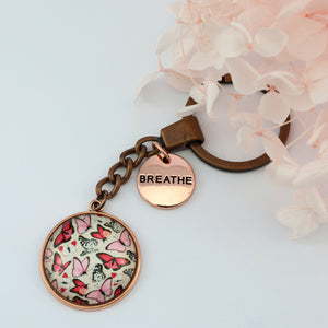 Pink floral print vintage copper circle pendant keychain with rose gold circle shape 'breathe' charm. Fundraising product for the National Breast Cancer Foundation. 