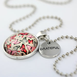 Pink floral print silver circle pendant necklace with ball chain with rose gold circle shape 'grateful' charm. Fundraising product for the National Breast Cancer Foundation. 