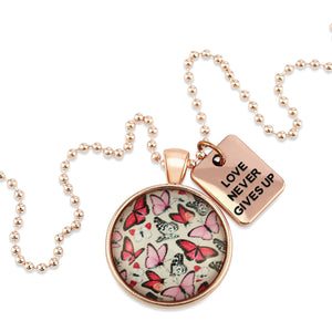 Pink floral print circle pendant rose gold necklace with ball chain with 'love never gives up' word charm. Fundraising product for the National Breast Cancer Foundation. 