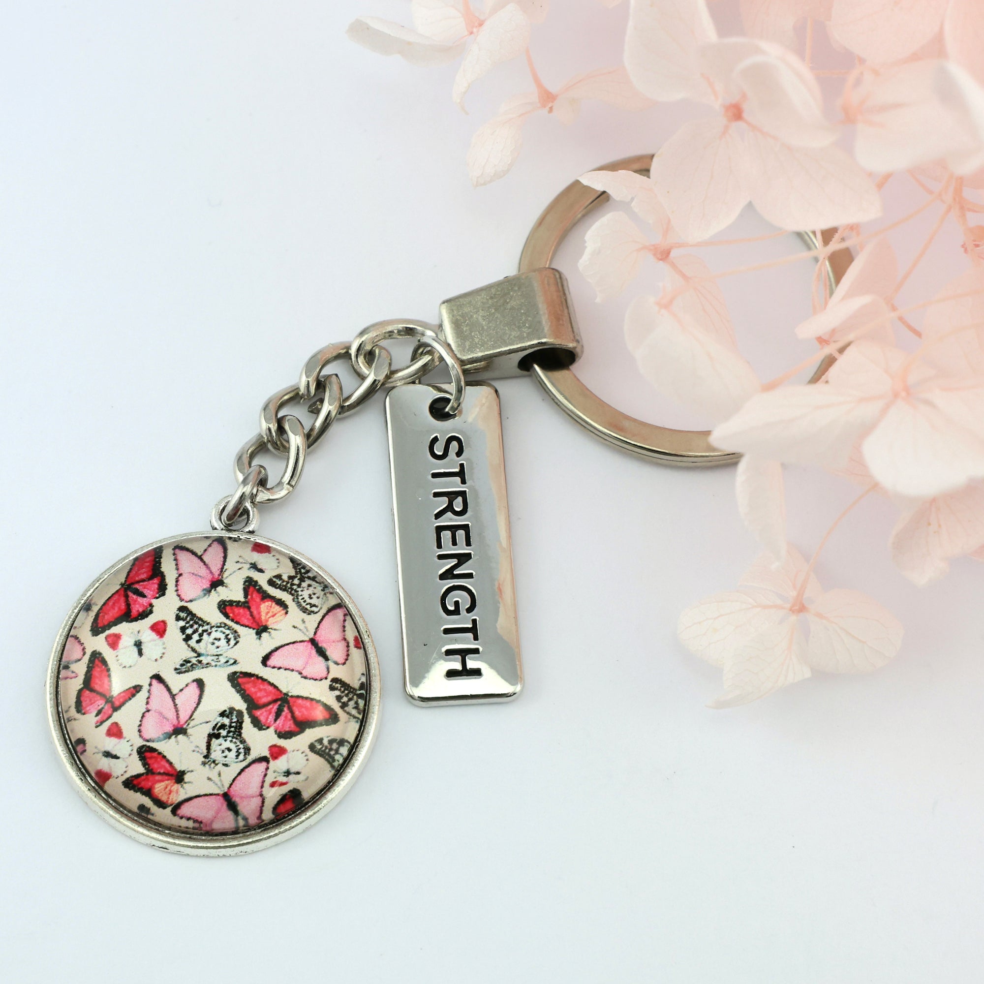 Pink butterfly print vintage silver keychain with strength charm. A product that fundraises for the National Breast Cancer Foundation. 