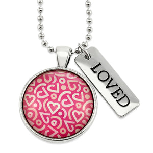 Pink heart print silver circle pendant necklace with 'loved' charm. A fundraising product for the national breast cancer foundation. 