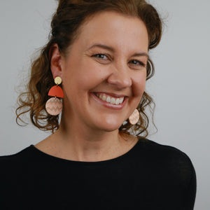 Woman wearing statement dangles ion bold orange and gold colour tones.