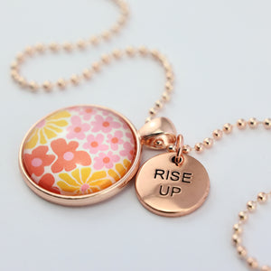 Pink floral print circle pendant silver ball chain necklace with rose gold 'rise up' word charm. Fundraising product for the National Breast Cancer Foundation. 