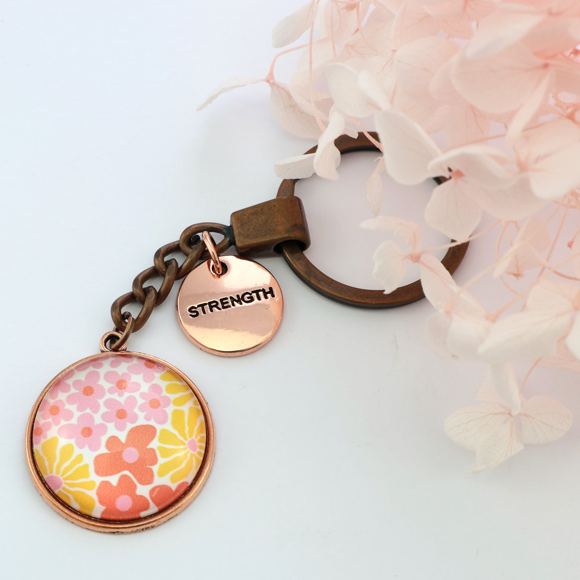 Pink floral print circle pendant vintage copper keychain with rose gold 'strength' word charm. Fundraising product for the National Breast Cancer Foundation. 