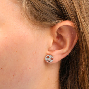 Stainless steel hypoallergenic soccer foorball stud earring, presented on a foil card that says strong and courageous. Pictured in eras. 