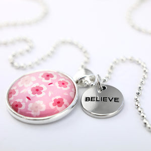 Pink floral print circle pendant silver ball chain necklace with silver 'believe' word charm. Fundraising product for the National Breast Cancer Foundation. 