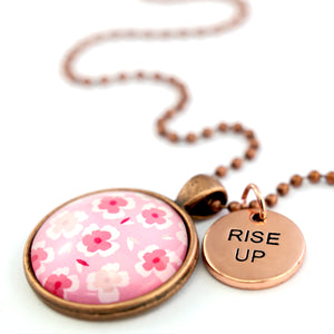 Pink floral print circle pendant vintage red copper ball chain necklace with rose gold 'rise up' word charm. Fundraising product for the National Breast Cancer Foundation. 