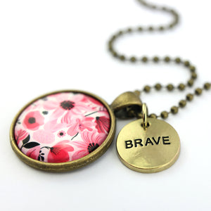 Pink floral print circle pendant vintage gold ball chain necklace with gold 'brave' word charm. Fundraising product for the National Breast Cancer Foundation. 